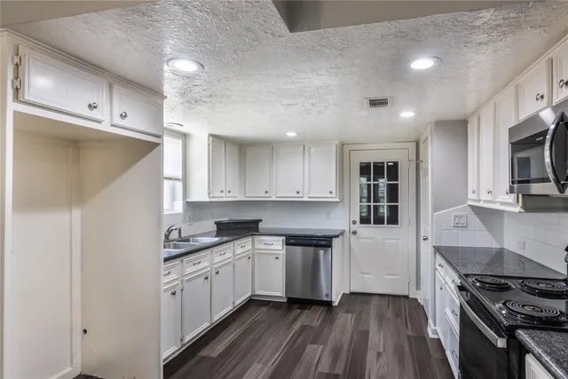 a kitchen with a white cabinets and wooden floor