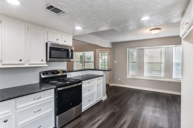 a kitchen with stainless steel appliances granite countertop a stove a sink and white cabinets