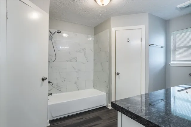 a bathroom with a granite countertop bathtub shower and toilet