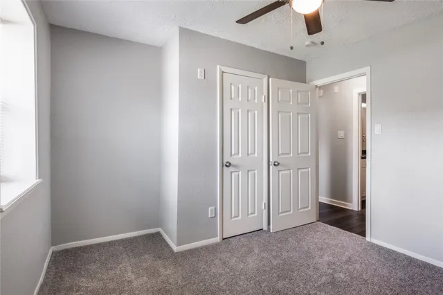an empty room with a ceiling fan and a window