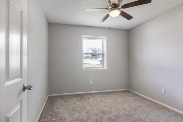 an empty room with a window and a fan