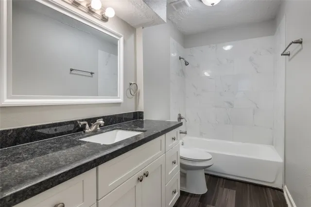 a bathroom with a granite countertop sink a toilet and bathtub