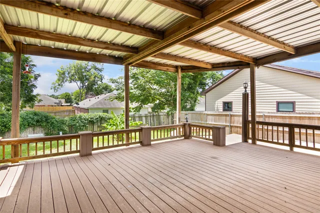 a view of a deck with wooden floor and roof with a garden view
