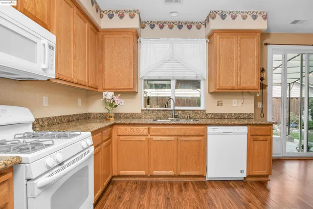 a kitchen with stainless steel appliances granite countertop wooden cabinets a sink and a stove