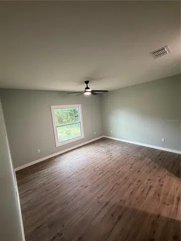 an empty room with windows and ceiling fan