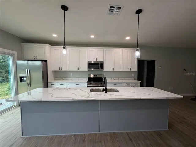 a large kitchen with kitchen island a counter space a sink appliances and cabinets