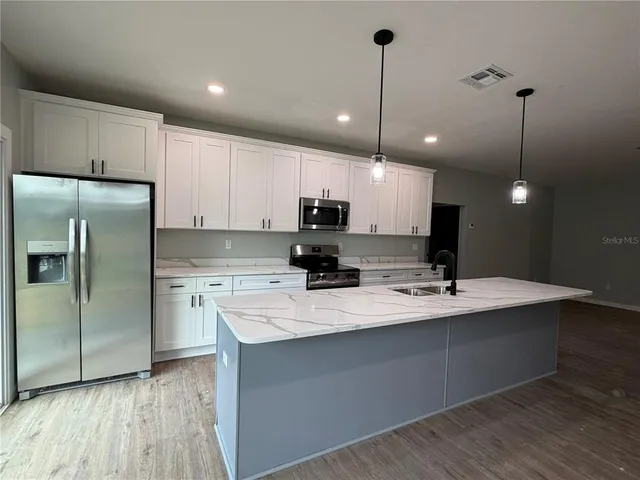 a kitchen with kitchen island a counter space a sink appliances and cabinets