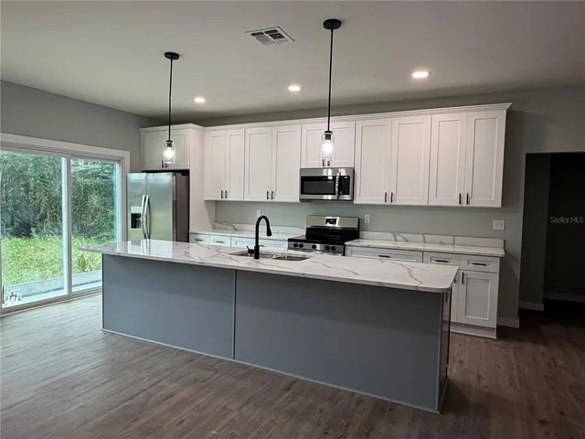 a kitchen with stainless steel appliances granite countertop a sink a stove and a refrigerator