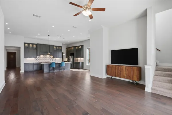 a view of an empty room with wooden floor and a ceiling fan