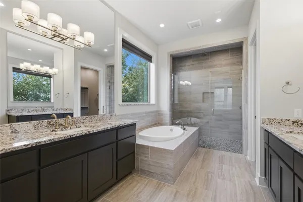 a spacious bathroom with a granite countertop double vanity sink a large mirror and a shower