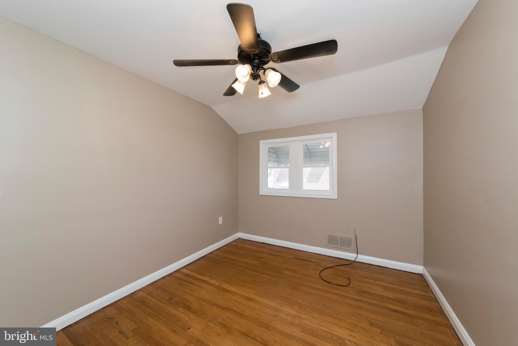 2702 Kirkleigh Road Baltimore, MD 21222 - Photo 20 of 32 an empty room with wooden floor ceiling fan and window