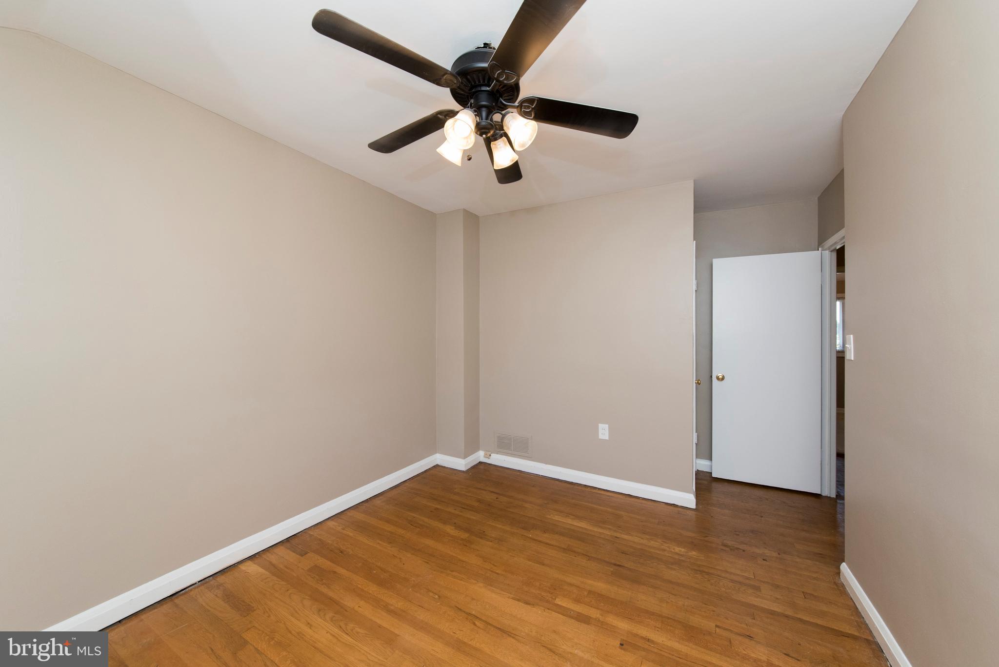 2702 Kirkleigh Road Baltimore, MD 21222 - Photo 21 of 32 an empty room with wooden floor and a ceiling fan