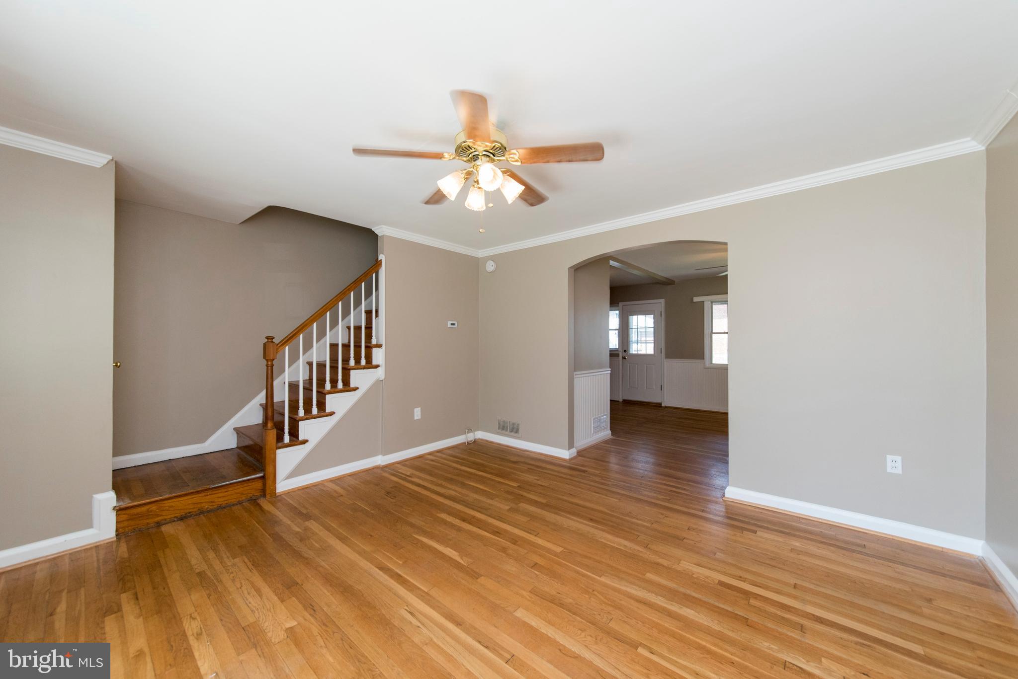 2702 Kirkleigh Road Baltimore, MD 21222 - Photo 4 of 32 a view of an empty room with wooden floor and a ceiling fan