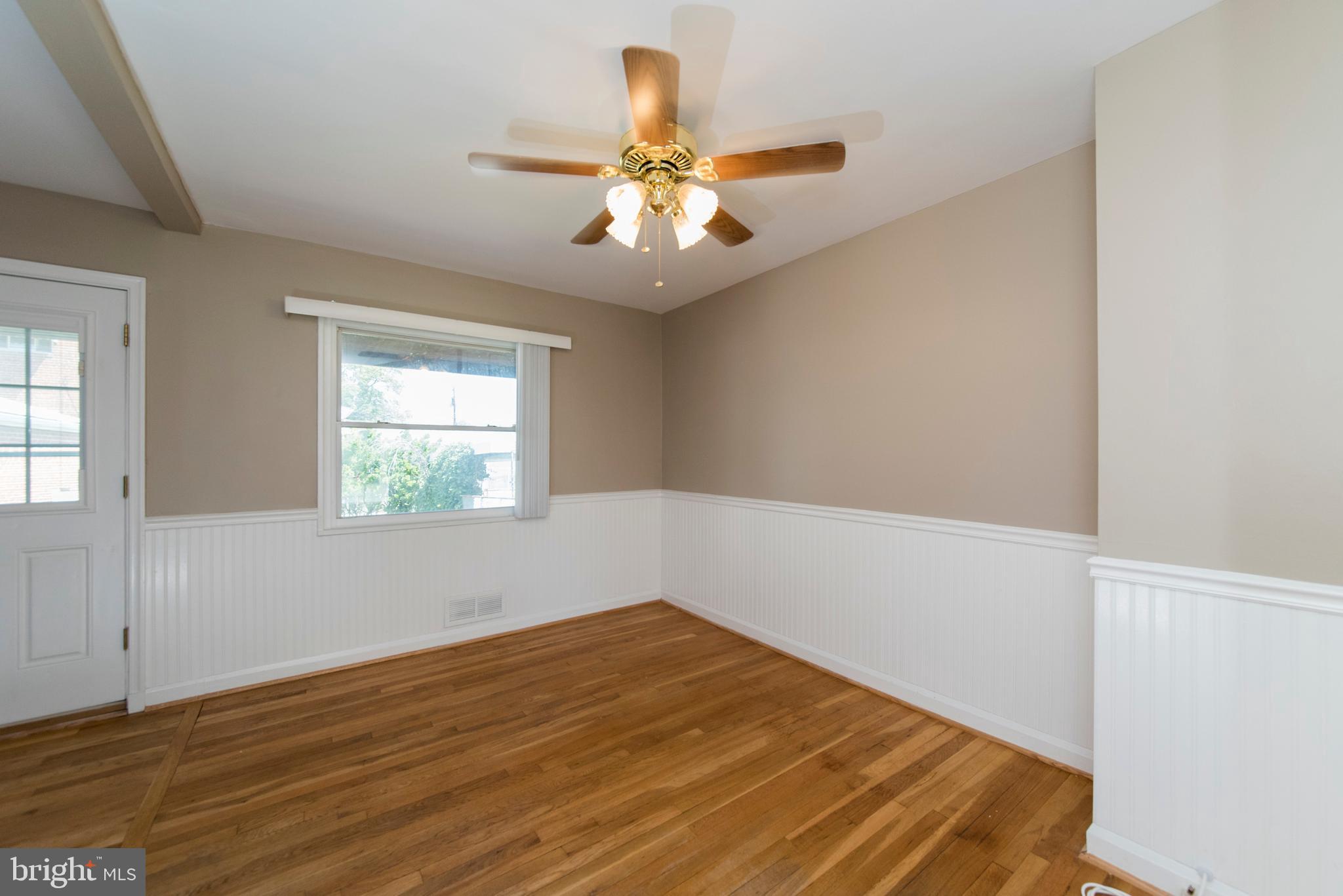 2702 Kirkleigh Road Baltimore, MD 21222 - Photo 8 of 32 an empty room with wooden floor fan and windows