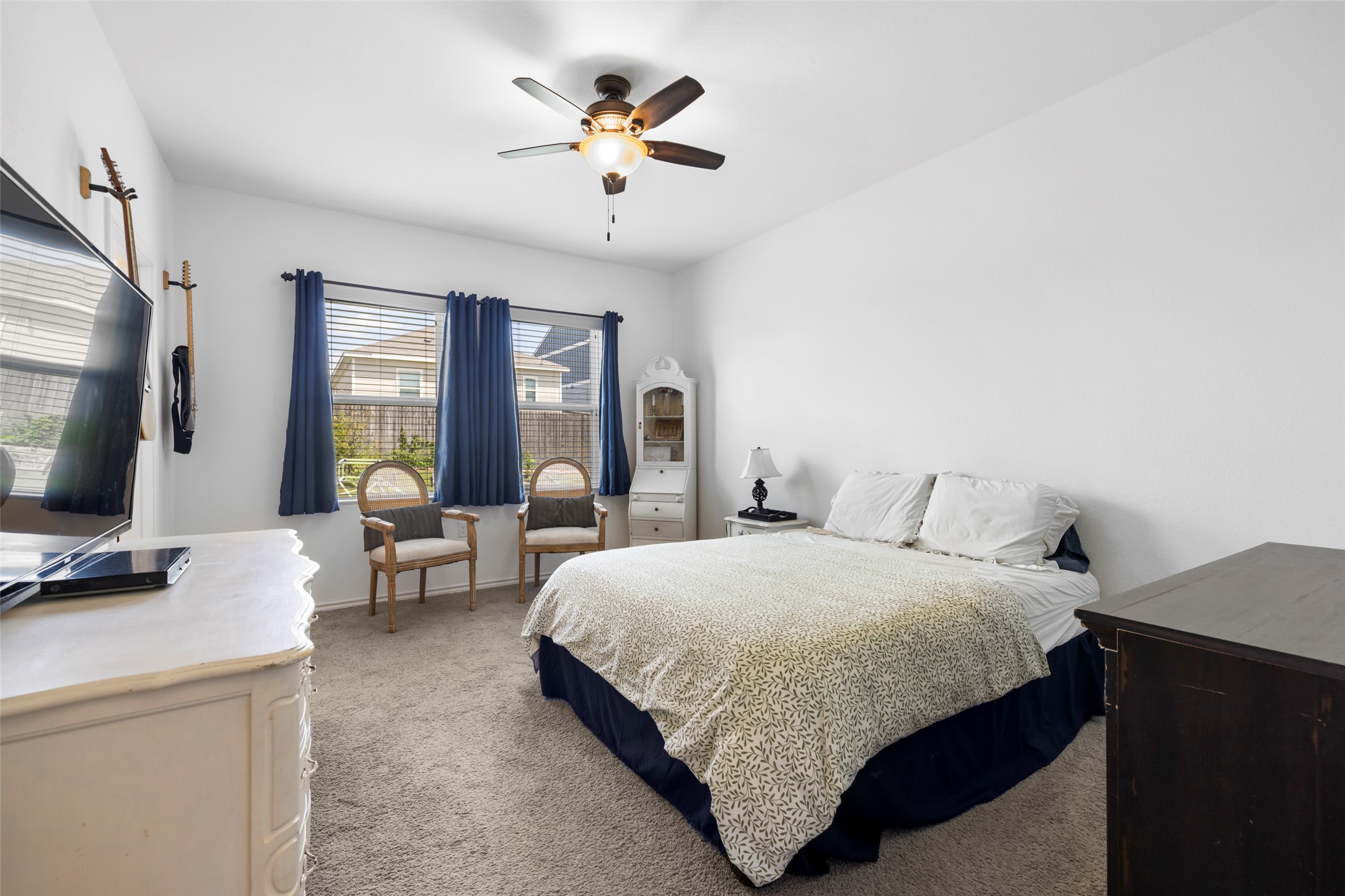 13113 Titanium Street Austin, TX 78754 - Photo 15 of 39 Primary bedroom featuring light colored carpet , a ceiling fan and large windows looking out onto the private backyard.