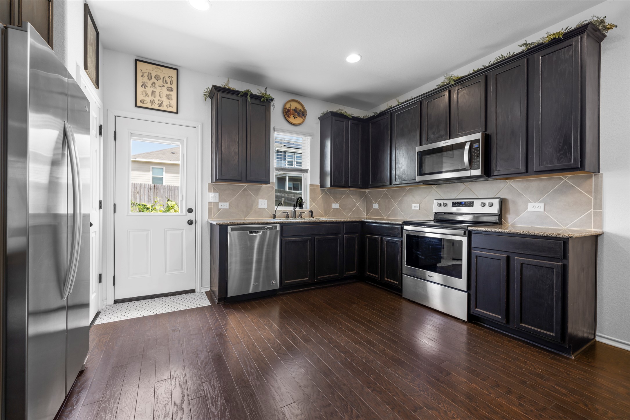 13113 Titanium Street Austin, TX 78754 - Photo 4 of 39 Kitchen with stainless appliances, engineered wood floors, tasteful backsplash, light granite counters, and recessed lighting