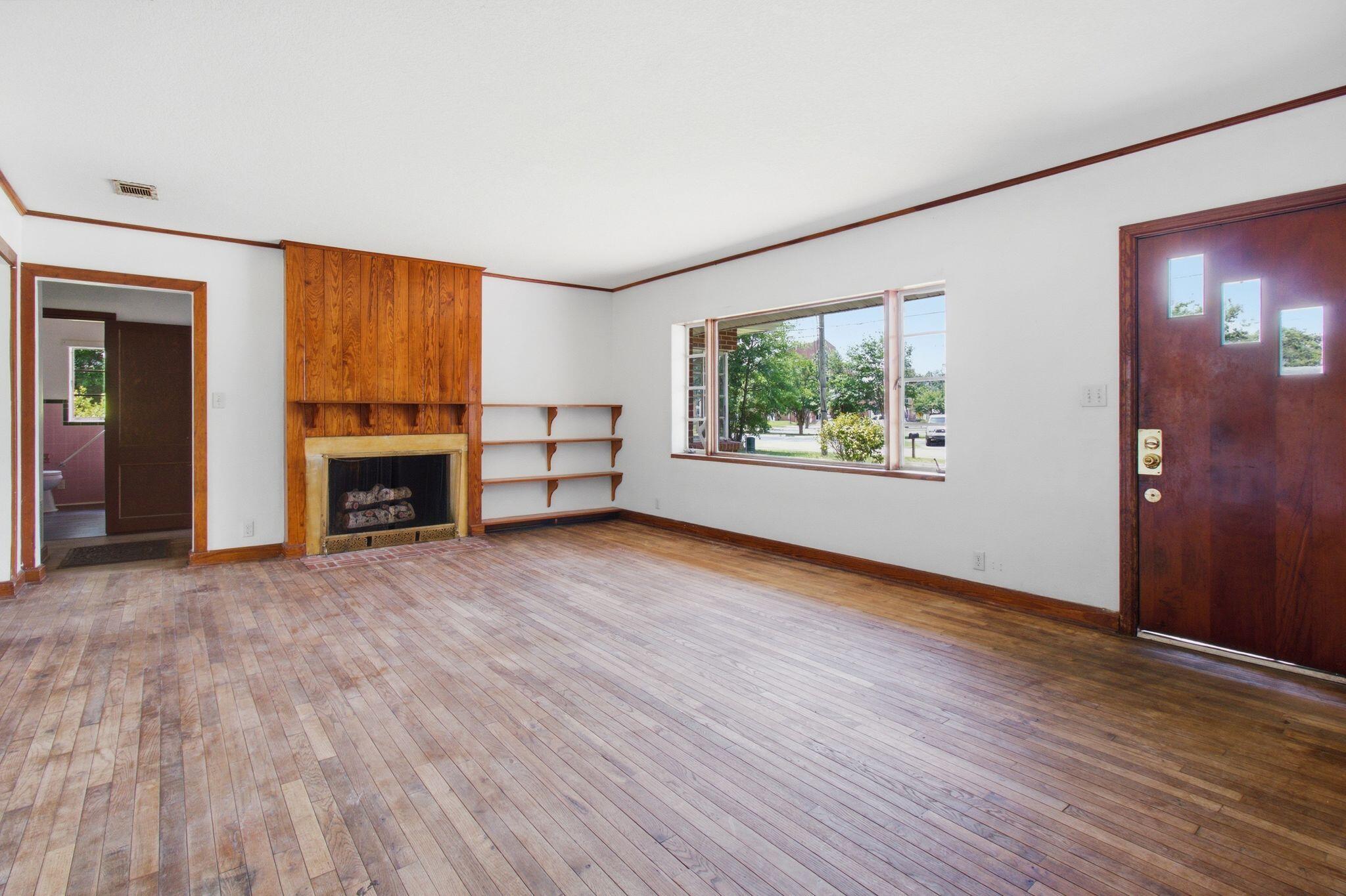 855 North Pearl Street Crestview, FL 32536 - Photo 2 of 31 an empty room with wooden floor fire place and windows