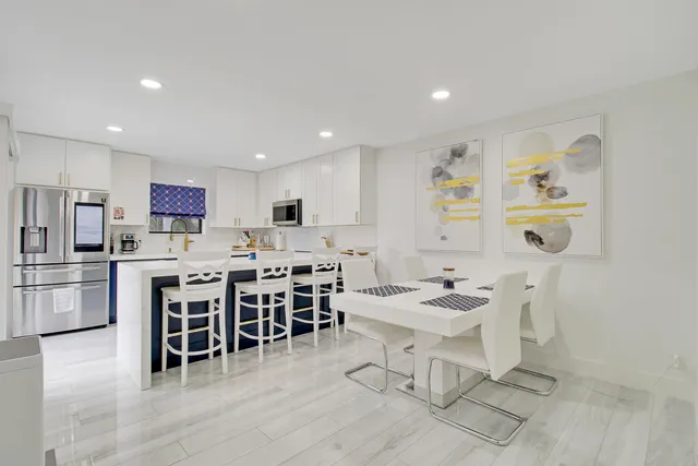 a living room with stainless steel appliances lots of white furniture a dining table and chairs