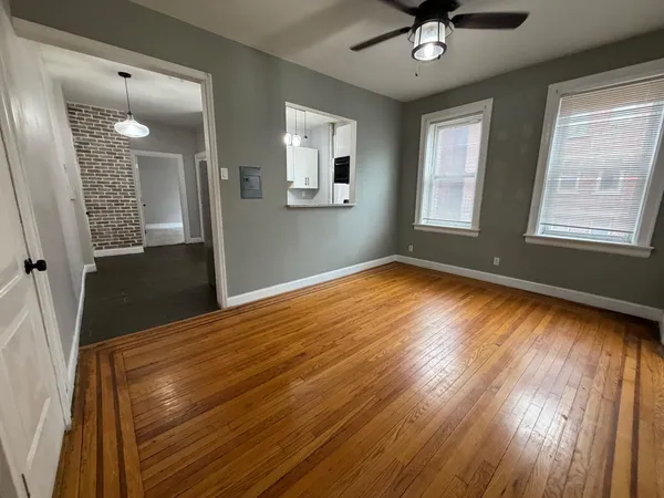 a view of an empty room with a window and wooden floor