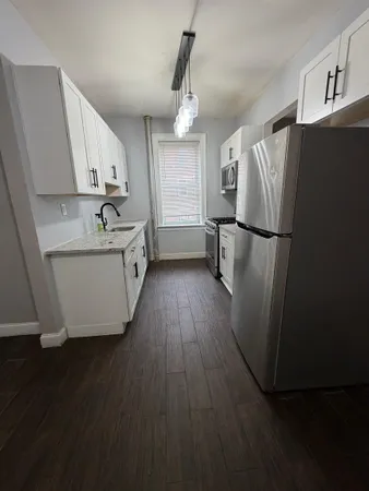 a kitchen with a refrigerator a sink and wooden floor