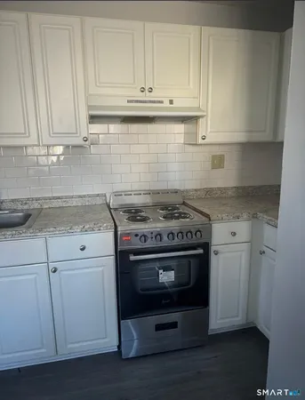 a kitchen with granite countertop white cabinets and stainless steel appliances