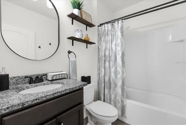 a bathroom with a granite countertop sink a toilet and shower