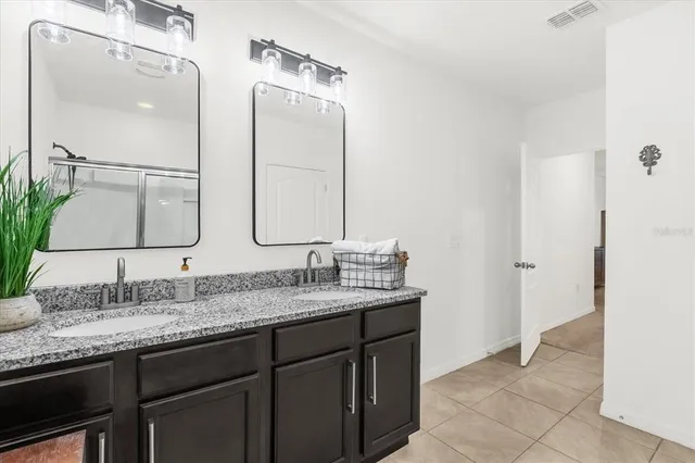 a bathroom with a granite countertop double vanity sink and a mirror