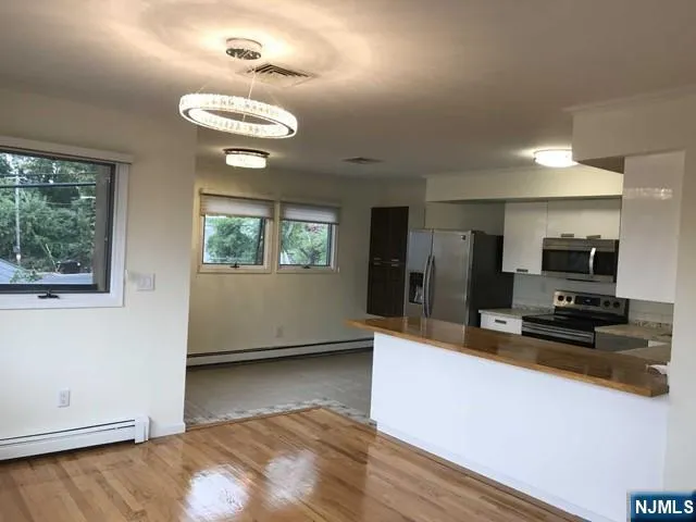 a kitchen with kitchen island granite countertop a stove top oven a sink dishwasher a dining table and chairs with wooden floor