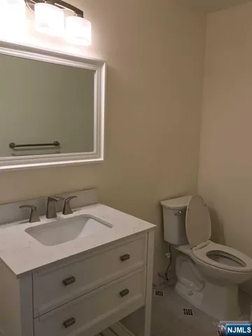 a bathroom with a toilet sink vanity and mirror