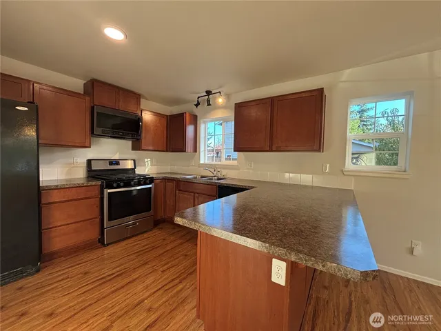 a kitchen with granite countertop a refrigerator and a stove top oven