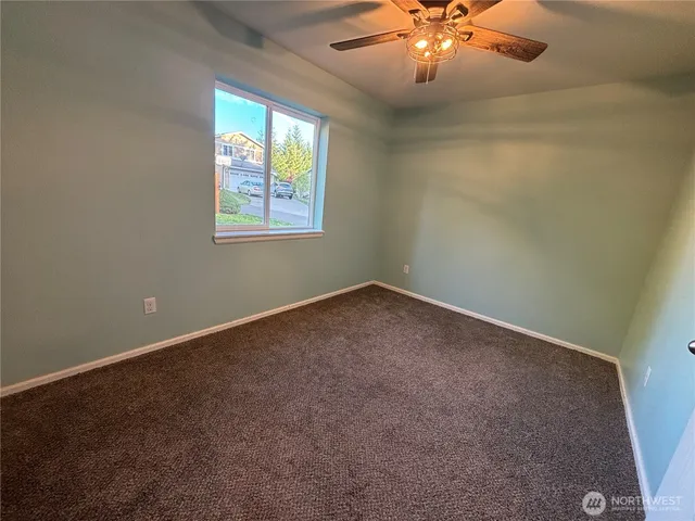 an empty room with windows and chandelier fan