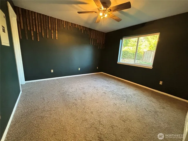 an empty room with windows and fan