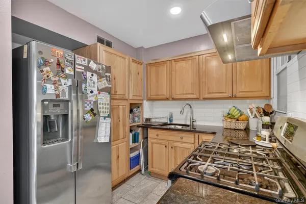 a kitchen with stainless steel appliances kitchen island granite countertop a refrigerator and a sink