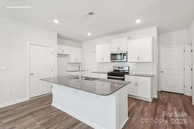 a kitchen with granite countertop a sink stove and refrigerator
