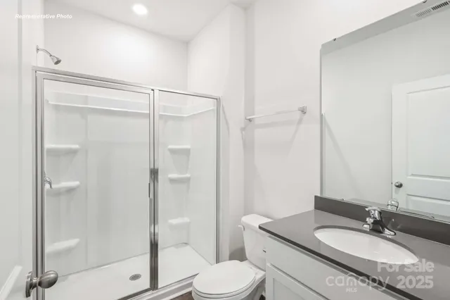 a bathroom with a granite countertop sink toilet mirror and shower