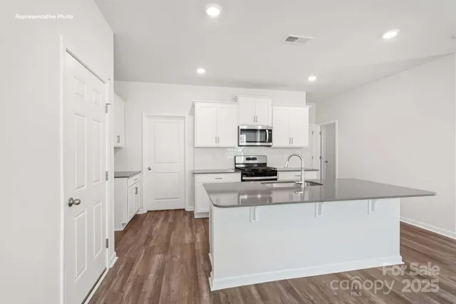 a large kitchen with stainless steel appliances a large counter top a stove a sink dishwasher and a refrigerator