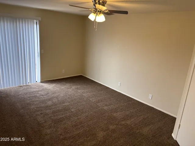 an empty room with a chandelier fan and windows