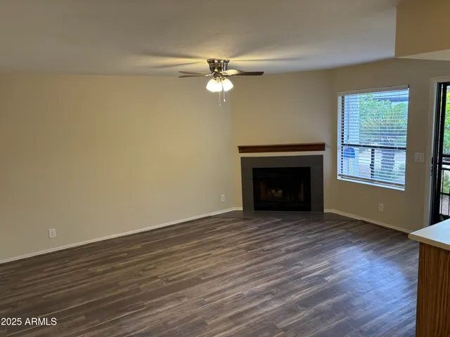 a view of an empty room with wooden floor fireplace and a window