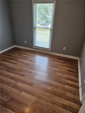 a view of empty room with window and wooden floor