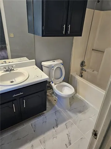 a bathroom with a granite countertop toilet sink and mirror