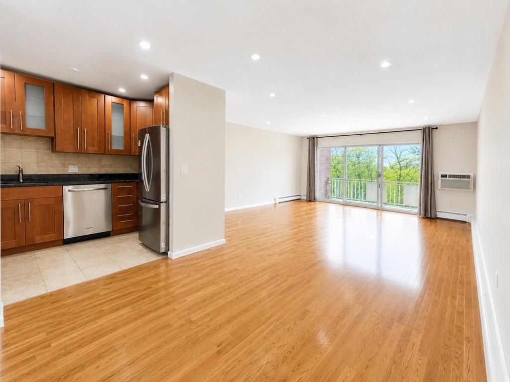 383 Langley Road, Unit 11 Newton, MA 02459 - Photo 2 of 15 a view of a kitchen with stainless steel appliances granite countertop a refrigerator a stove top oven a sink and dishwasher with wooden floor
