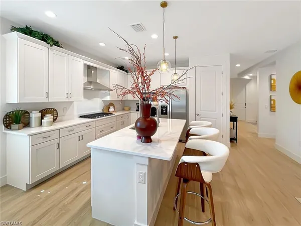 a kitchen with stainless steel appliances kitchen island a white table chairs and a wooden floor