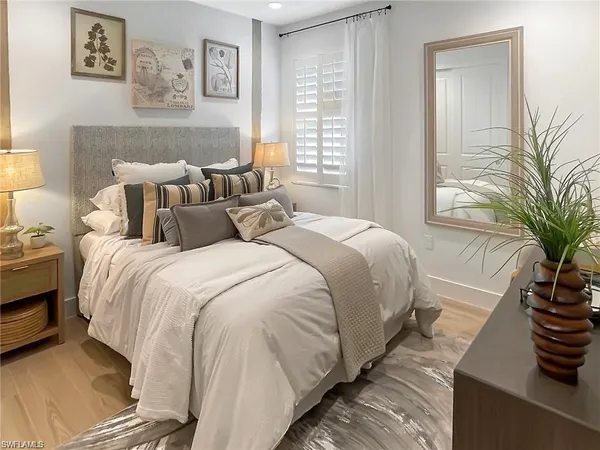 a bedroom with bed and a potted plant on the dresser