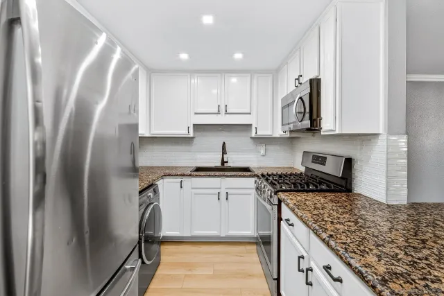 a kitchen with stainless steel appliances granite countertop a stove and a refrigerator