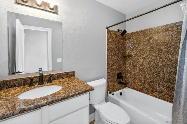 a bathroom with a granite countertop sink toilet and shower