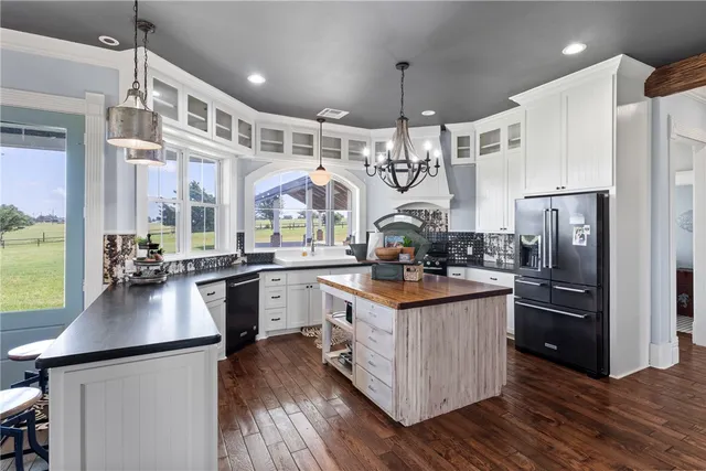 a kitchen with stainless steel appliances granite countertop a stove a sink dishwasher a dining table and chairs with wooden floor