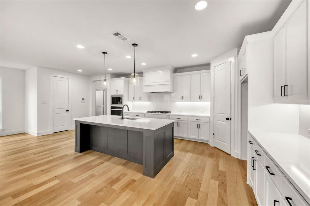 3420 Brocco Road Celina, TX 75009 - Photo 13 of 27 Spacious kitchen featuring an expansive center island, white cabinetry, integrated stainless steel appliances, wood-finish flooring, and recessed lighting