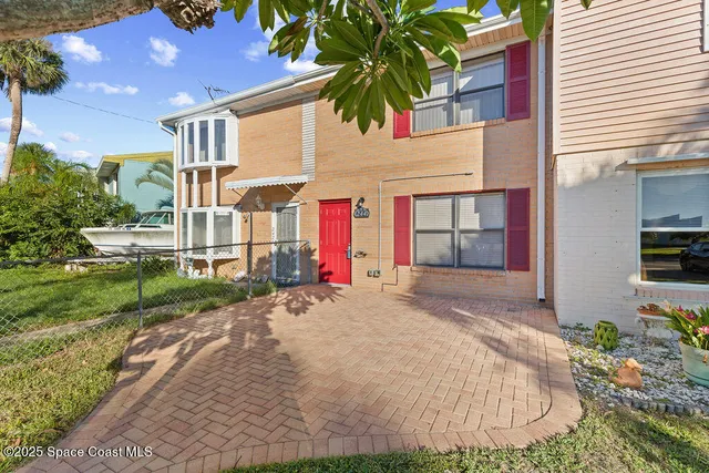 a front view of a house with a yard and potted plants