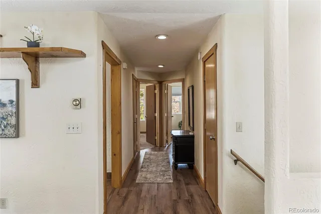 a view of a hallway with wooden floor and a bathroom