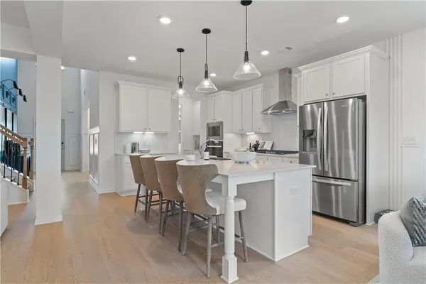 a kitchen with stainless steel appliances kitchen island granite countertop a refrigerator a stove a kitchen island with a dining table and chairs